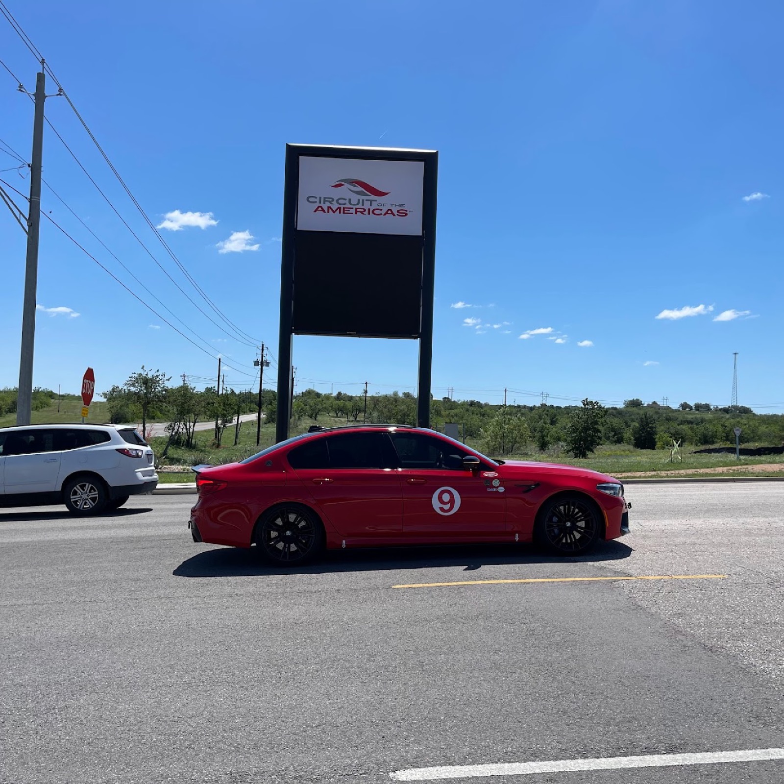 My red BMW M5 with its number 9 roundel, parked at the Circuit of the Americas entrance sign