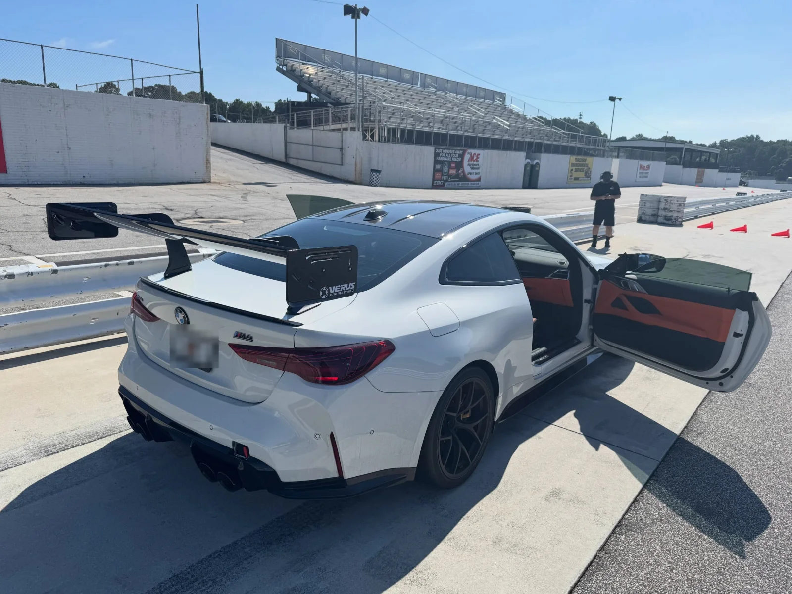 The M4 in the paddock with both doors open, rear wing and diffuser visible